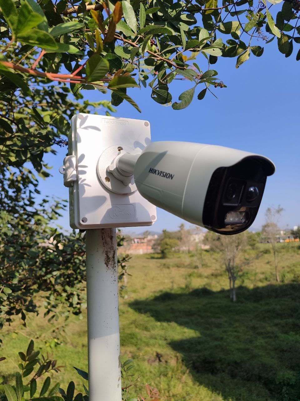 Câmera Hikvision em poste com caixa de passagem, em área aberta